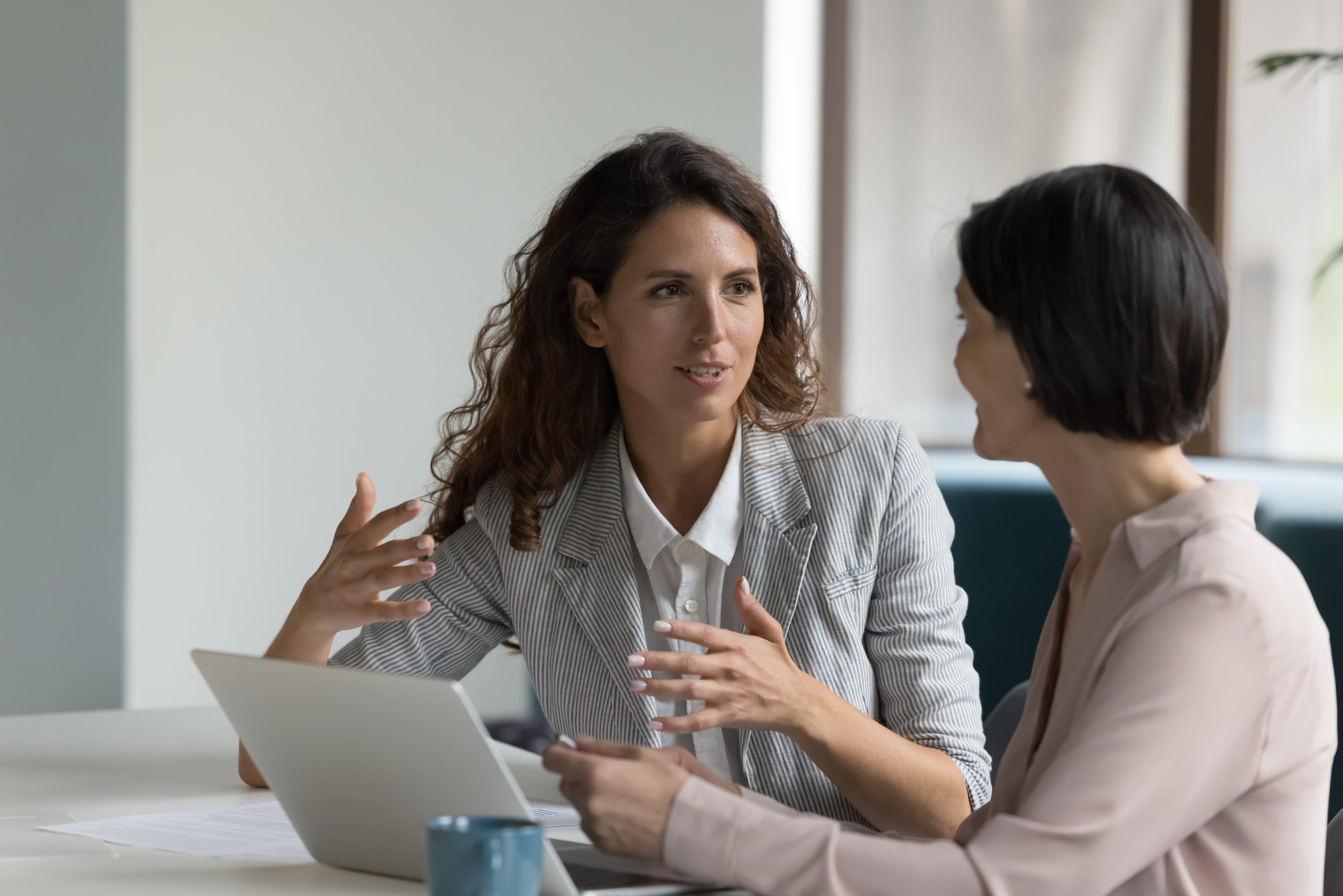 Two colleagues discussing work at laptop