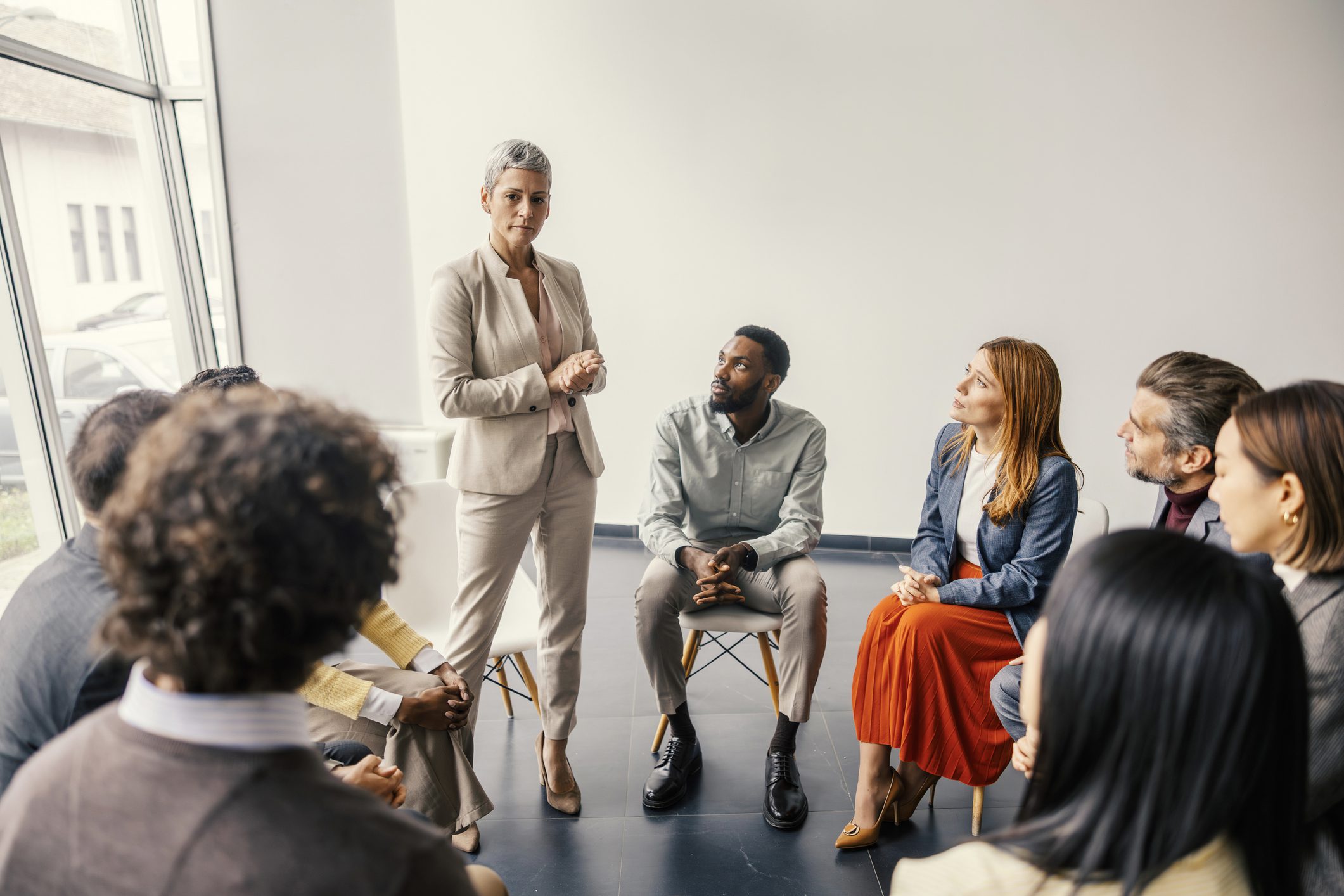 Facilitator leading diverse group meeting in circle