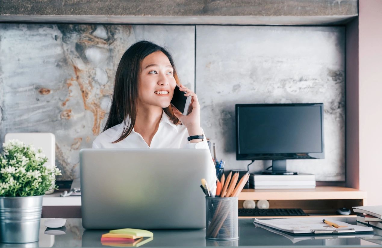 Woman talking on phone at laptop desk