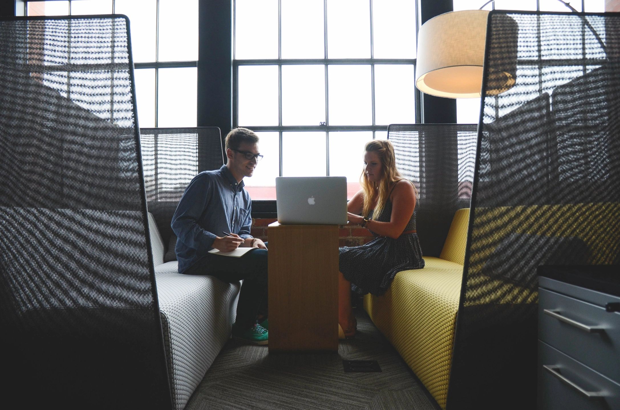 Two coworkers collaborating on laptop in booth