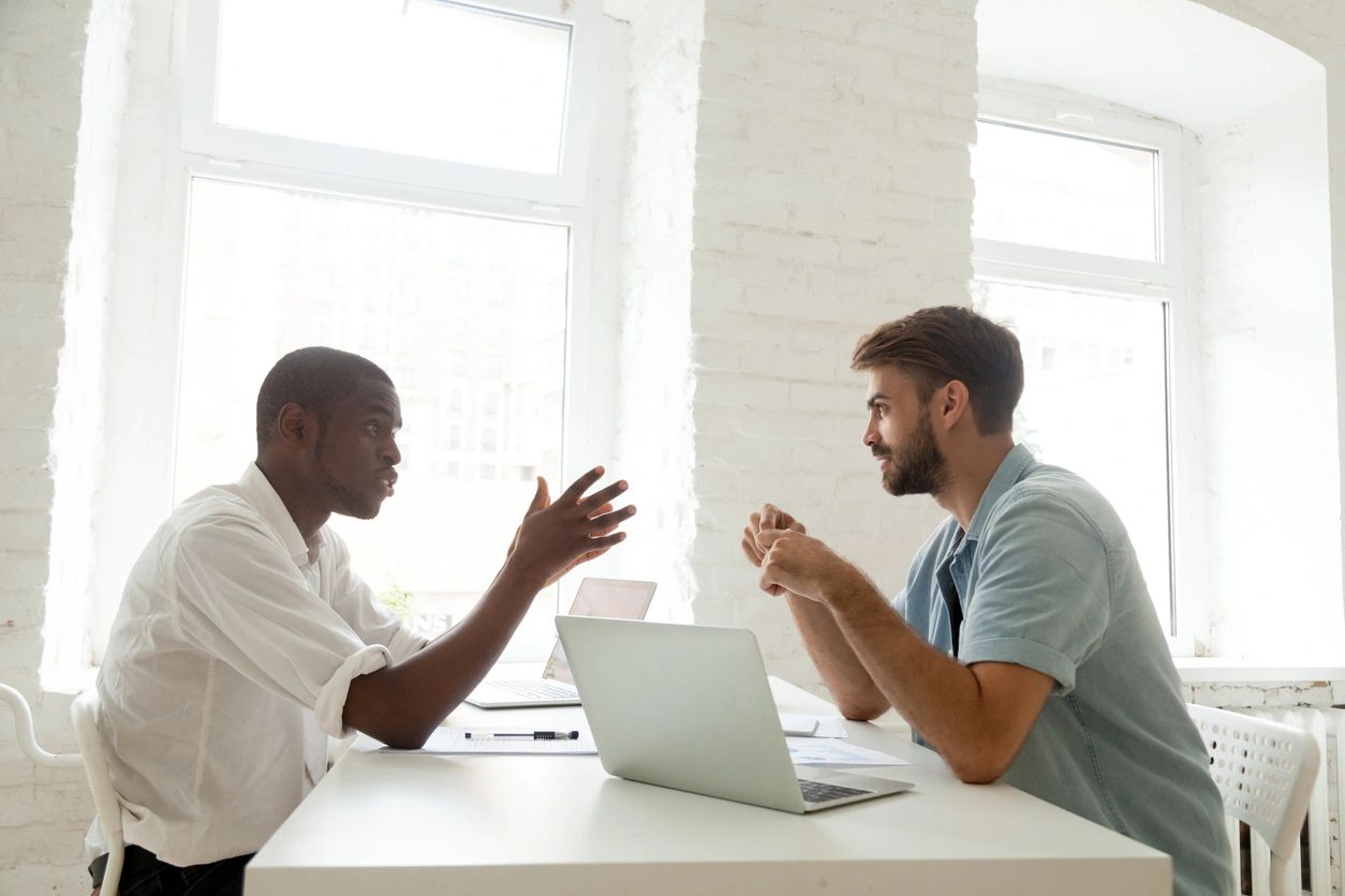 Two colleagues discussing at desk with laptop