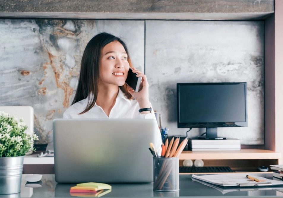 Woman talking on phone at laptop desk