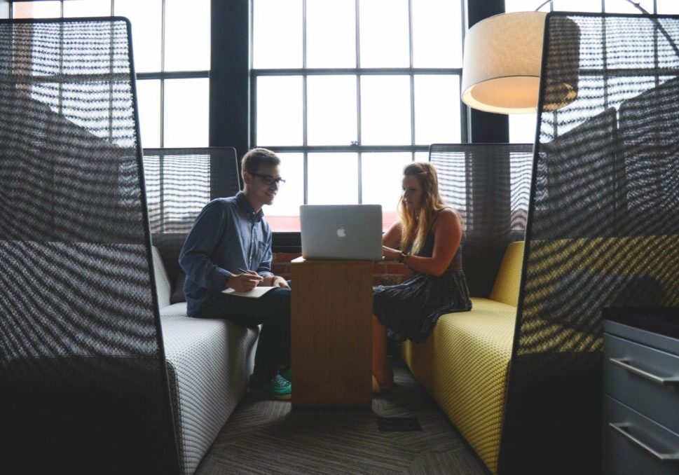 Two coworkers collaborating on laptop in booth